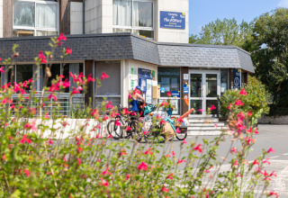 Entrada de Flower Camping L'Ile d'Offard en Pays de la Loire, Francia, con ciclistas y flores en primer plano.