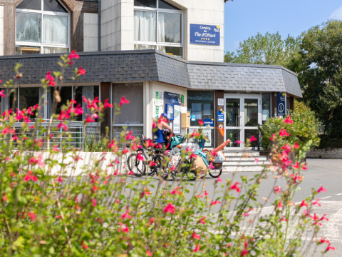 Entrada de Flower Camping L'Ile d'Offard en Pays de la Loire, Francia, con ciclistas y flores en primer plano.