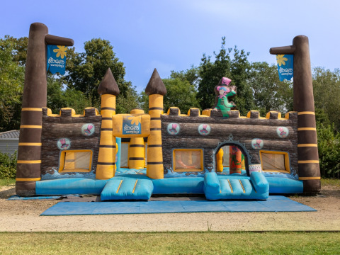 Castillo inflable para niños en Flower Camping L'Ile d'Offard, rodeado de árboles en Pays de la Loire, Francia.