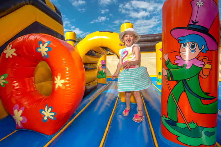 Smiling child playing on a colorful bouncy castle at Flower Camping L'Ile d'Offard, Pays de la Loire, France.