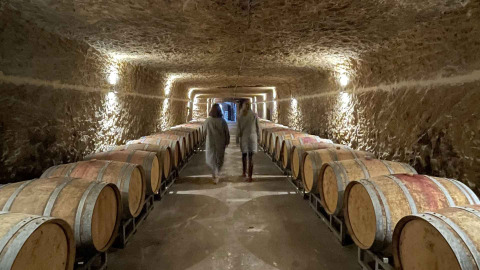 Twee mensen lopen door een wijnkelder met houten vaten nabij Saumur, Pays de la Loire, Frankrijk.