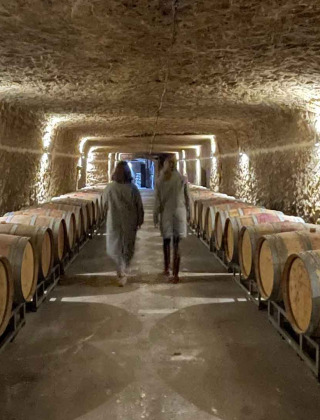 Twee mensen lopen door een wijnkelder met houten vaten nabij Saumur, Pays de la Loire, Frankrijk.