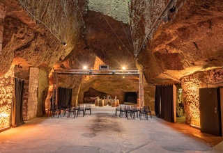 Underground stone hall with chairs and lighting, photographed at Flower Camping L'Ile d'Offard, Pays de la Loire.