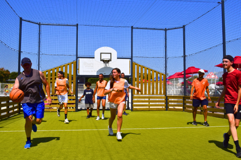 Gruppo di persone gioca a basket all'aperto presso Flower Camping Les Ilates in Nouvelle-Aquitaine, Francia.