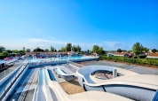 Außenpoolbereich mit Wasserrutschen und Sonnenliegen im Flower Camping Les Ilates, Nouvelle-Aquitaine, Frankreich.