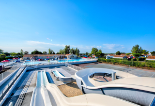 Area piscina all'aperto con scivoli d'acqua e lettini al Flower Camping Les Ilates in Nouvelle-Aquitania, Francia.
