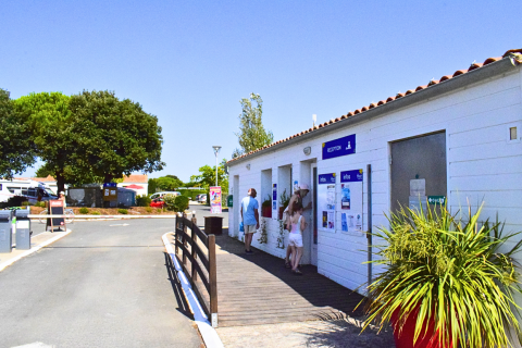 Recepción de Flower Camping Les Ilates en Nouvelle-Aquitaine, Francia, en un día soleado con visitantes.