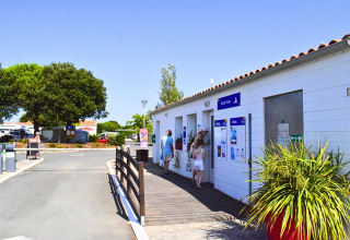 Recepción de Flower Camping Les Ilates en Nouvelle-Aquitaine, Francia, en un día soleado con visitantes.