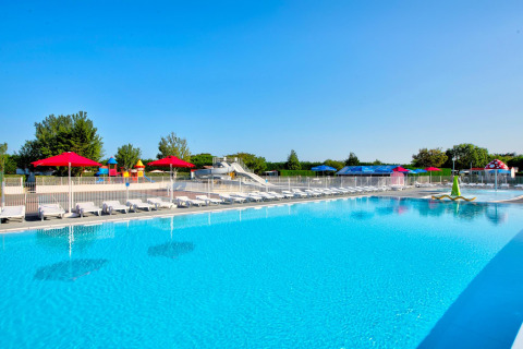 Außenpool mit Liegestühlen, roten Sonnenschirmen und Wasserrutsche im Flower Camping Les Ilates, Nouvelle-Aquitaine, Frankreich.
