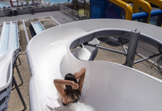 Eine Person rutscht eine gewundene Wasserrutsche im Flower Camping Les Ilates in Nouvelle-Aquitaine, Frankreich hinunter.