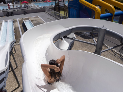 Una persona baja por un tobogán de agua en Flower Camping Les Ilates, un parque vacacional en Nouvelle-Aquitaine, Francia.