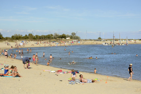 Gezinnen op het strand bij Flower Camping Les Ilates in Nouvelle-Aquitaine, Frankrijk, genieten van de zon.