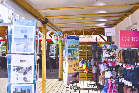 Buitenwinkel met postkaarten, slippers en souvenirs aan Flower Camping Les Ilates in Nouvelle-Aquitaine, Frankrijk.
