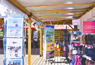 Buitenwinkel met postkaarten, slippers en souvenirs aan Flower Camping Les Ilates in Nouvelle-Aquitaine, Frankrijk.