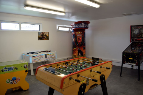 Sala de juegos con futbolín, máquinas recreativas y boxeador en Flower Camping Les Ilates, Nouvelle-Aquitania, Francia.