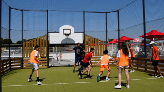 Menschen spielen Ball auf einem Außenplatz im Flower Camping Les Ilates, Nouvelle-Aquitaine, Frankreich.