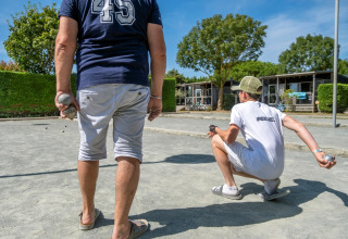 Gæster spiller petanque på grusbanen i Flower Camping Les Ilates, en feriepark i Nouvelle-Aquitaine, Frankrig.