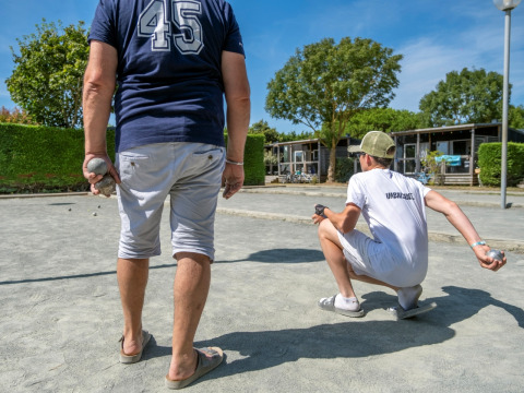 Ospiti che giocano a pétanque sul campo di ghiaia a Flower Camping Les Ilates, villaggio vacanze in Nuova Aquitania.