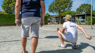 Gäste spielen Boule auf einem Sandplatz im Flower Camping Les Ilates, einem Ferienpark in Nouvelle-Aquitaine.