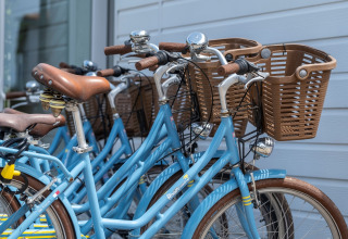 Biciclette azzurre con cestini parcheggiate vicino a un muro, foto scattata a Flower Camping Les Ilates in Francia.