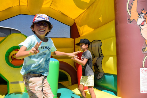 Dos niños sonríen y juegan dentro de un castillo hinchable en Flower Camping Les Ilates, Nouvelle-Aquitania, Francia.