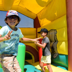 Deux enfants s’amusent et sourient dans un château gonflable à Flower Camping Les Ilates, Nouvelle-Aquitaine, France.