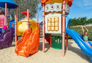 Bambini giocano su scivoli colorati e giochi nel parco giochi del Flower Camping Les Ilates in Francia.
