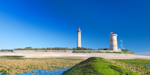Uitzicht op vuurtorens en zandstrand bij Flower Camping Les Ilates in Nouvelle-Aquitaine, Frankrijk, onder blauwe lucht.