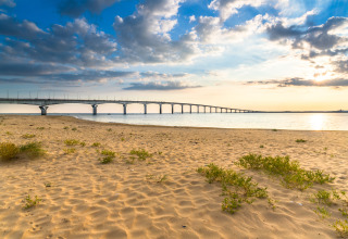 Ponte visto dalla spiaggia sabbiosa a Flower Camping Les Ilates, Nouvelle-Aquitaine, Francia, al tramonto.