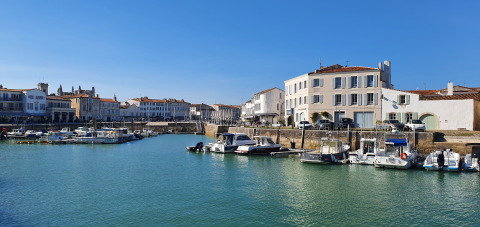 Hafen in der Nähe von Loix, Nouvelle-Aquitaine, Frankreich, mit Booten und historischen Häusern.