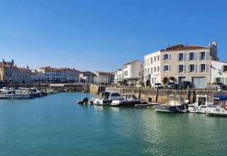 Vue sur le port près de Loix, Nouvelle-Aquitaine, France, avec bateaux amarrés et maisons traditionnelles.
