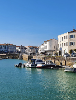 Hafen in der Nähe von Loix, Nouvelle-Aquitaine, Frankreich, mit Booten und historischen Häusern.
