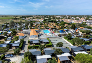 Luftfoto af Flower Camping Les Ilates feriepark i Nouvelle-Aquitaine, Frankrig, med pool og hytter.