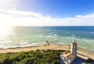 Panorama costiero vicino a Loix, Nouvelle-Aquitaine, Francia, con un vecchio faro e mare blu soleggiato.
