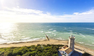 Küstenlandschaft bei Loix, Nouvelle-Aquitaine, Frankreich, mit Leuchtturm und sonnigem, ruhigem Meer.