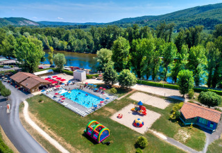 Aerial view of Flower Camping Les Ondines in Occitanie, France, featuring a pool, playground, and river scenery.