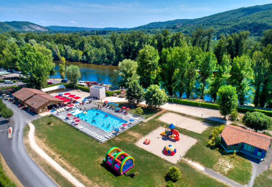 Vue aérienne de Flower Camping Les Ondines en Occitanie, France, avec piscine, aire de jeux et rivière proche.
