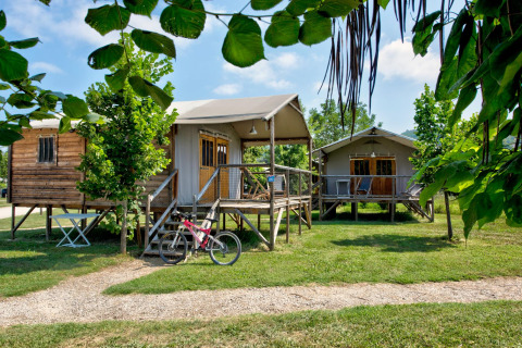 Op palen gebouwde huisjes tussen groene bomen bij Flower Camping Les Ondines, vakantiepark in Occitanië, Frankrijk.