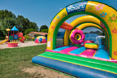 Speelplein met springkasteel en glijbanen bij Flower Camping Les Ondines, vakantiepark in Occitanie, Frankrijk.