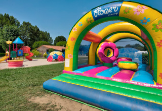 Speelplein met springkasteel en glijbanen bij Flower Camping Les Ondines, vakantiepark in Occitanie, Frankrijk.