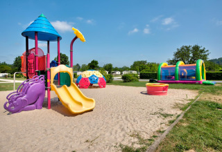 Farverigt legepladsområde med rutsjebane og oppustelig legetunnel på Flower Camping Les Ondines, Occitanie.