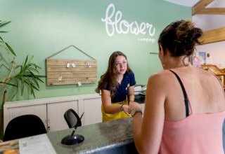 Receptionist byder gæst velkommen på Flower Camping Les Ondines, en feriepark i Occitanie, Frankrig.