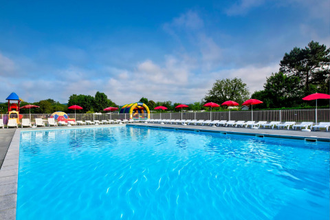 Piscina exterior con tumbonas, sombrillas rojas y zona de juegos en Flower Camping Les Ondines, Occitanie, Francia.