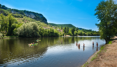 Persone che fanno il bagno e vanno in kayak sul fiume a Flower Camping Les Ondines in Occitania, Francia, tra le colline.