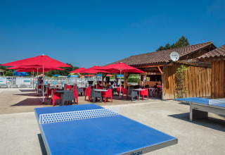 Terrasse extérieure avec parasols rouges au Flower Camping Les Ondines, Occitanie, France.