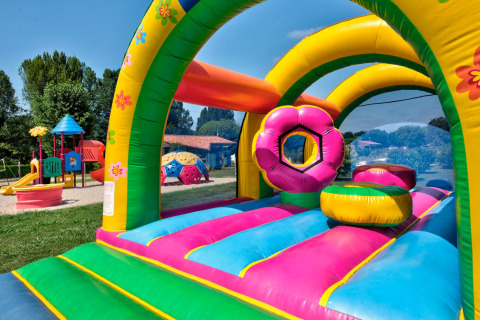 Colorful bouncy castle and playground at Flower Camping Les Ondines, Occitanie, France, on a sunny day.