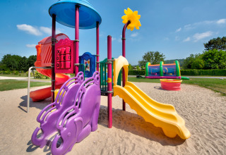 Parco giochi colorato con scivoli e giochi a Flower Camping Les Ondines in Occitania, Francia.