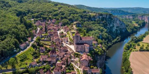 Vista aerea di Flower Camping Les Ondines, villaggio turistico in Occitania, Francia, accanto a fiume e colline verdi.