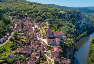 Aerial view of Flower Camping Les Ondines holiday park in Occitanie, France, beside a winding river and hills.