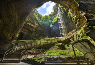 Indgang til Flower Camping Les Ondines grotte med metaltrapper, trækker lys og grønne planter i Occitanien.